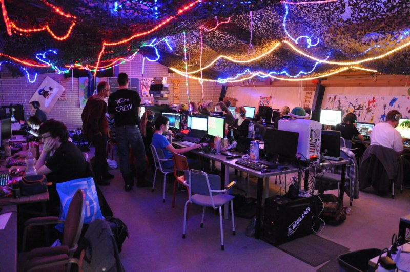 LAN-partyruimte vol pc's, met lichtjes en camouflagenetten aan het plafond
